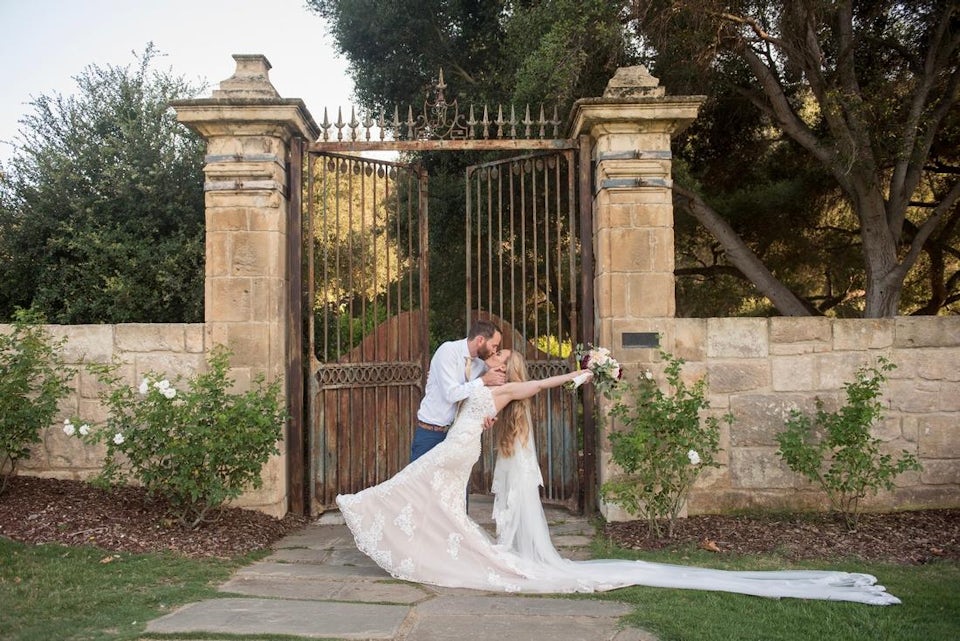 Just married couple kissing in front of a brick and iron gate